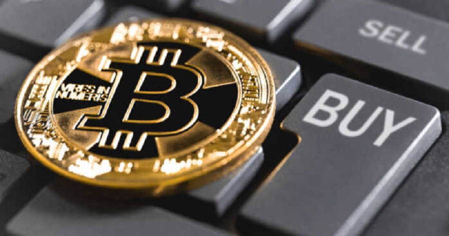 A bitcoin sitting on top of a computer keyboard with buttons labeled buy and sell