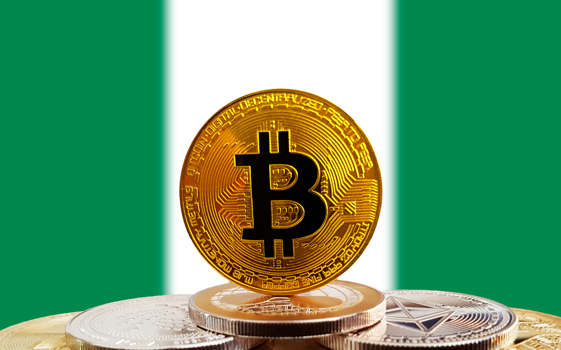 Bitcoin standing on top of other bitcoins with a Nigerian flag in the background