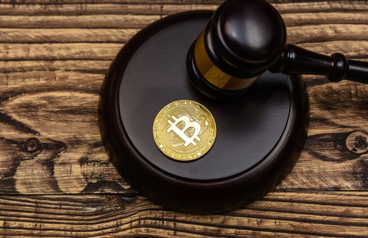 Picture of a bitcoin sitting on top a mallet, with a gavel resting next to it