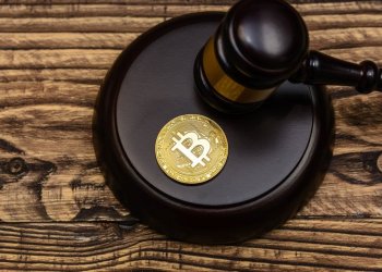Picture of a bitcoin sitting on top a mallet, with a gavel resting next to it