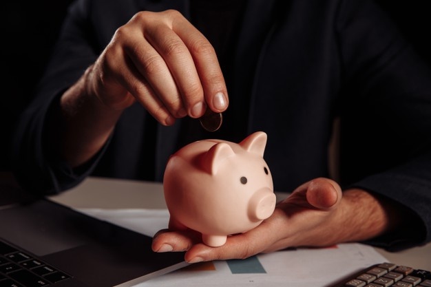 Picture of a hand putting a coin in a piggybank