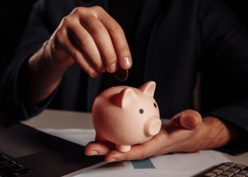 Picture of a hand putting a coin in a piggybank