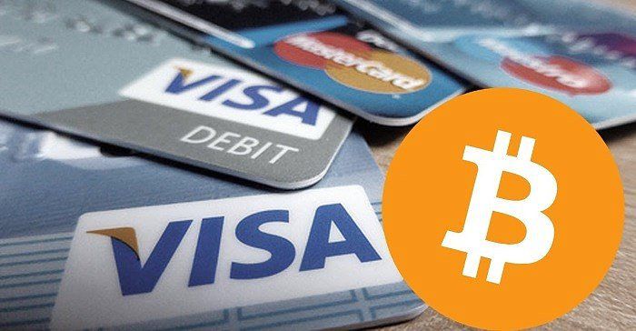 Picture of a bitcoin logo with Visa and MasterCard debit cards behind it