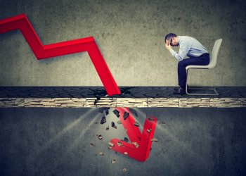 Picture of a man sitting with his head in his hands, while a red arrow crashes into the ground in front of him