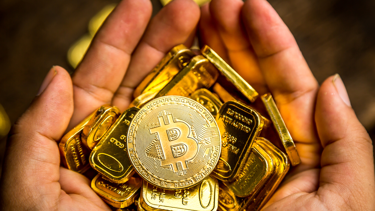 Picture of a hand holding gold blocks with a gold bitcoin on top of it