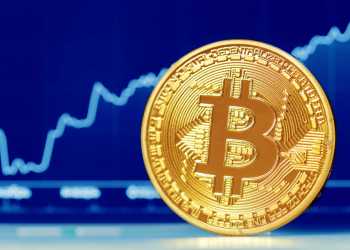 Picture of a bitcoin in front of a blue market chart