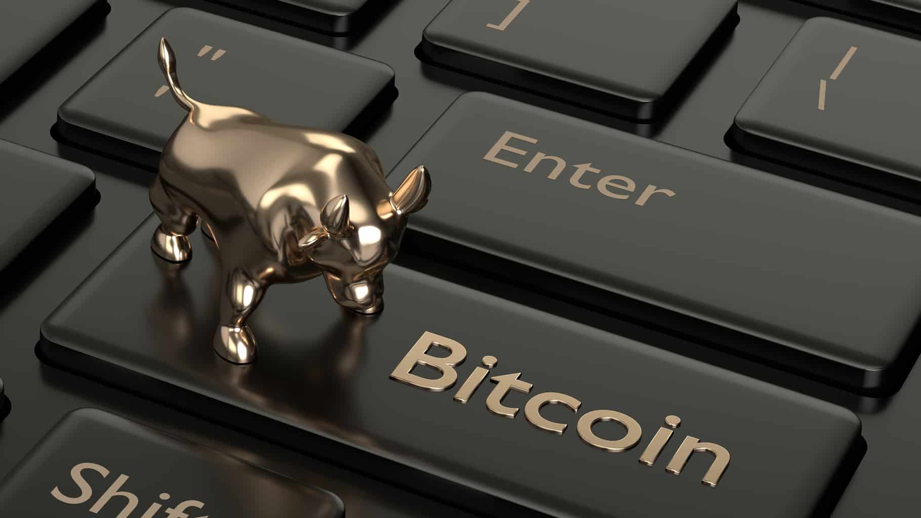 Picture of a gold bull on top a computer key with Bitcoin written on it