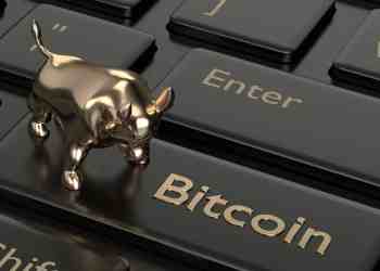 Picture of a gold bull on top a computer key with Bitcoin written on it