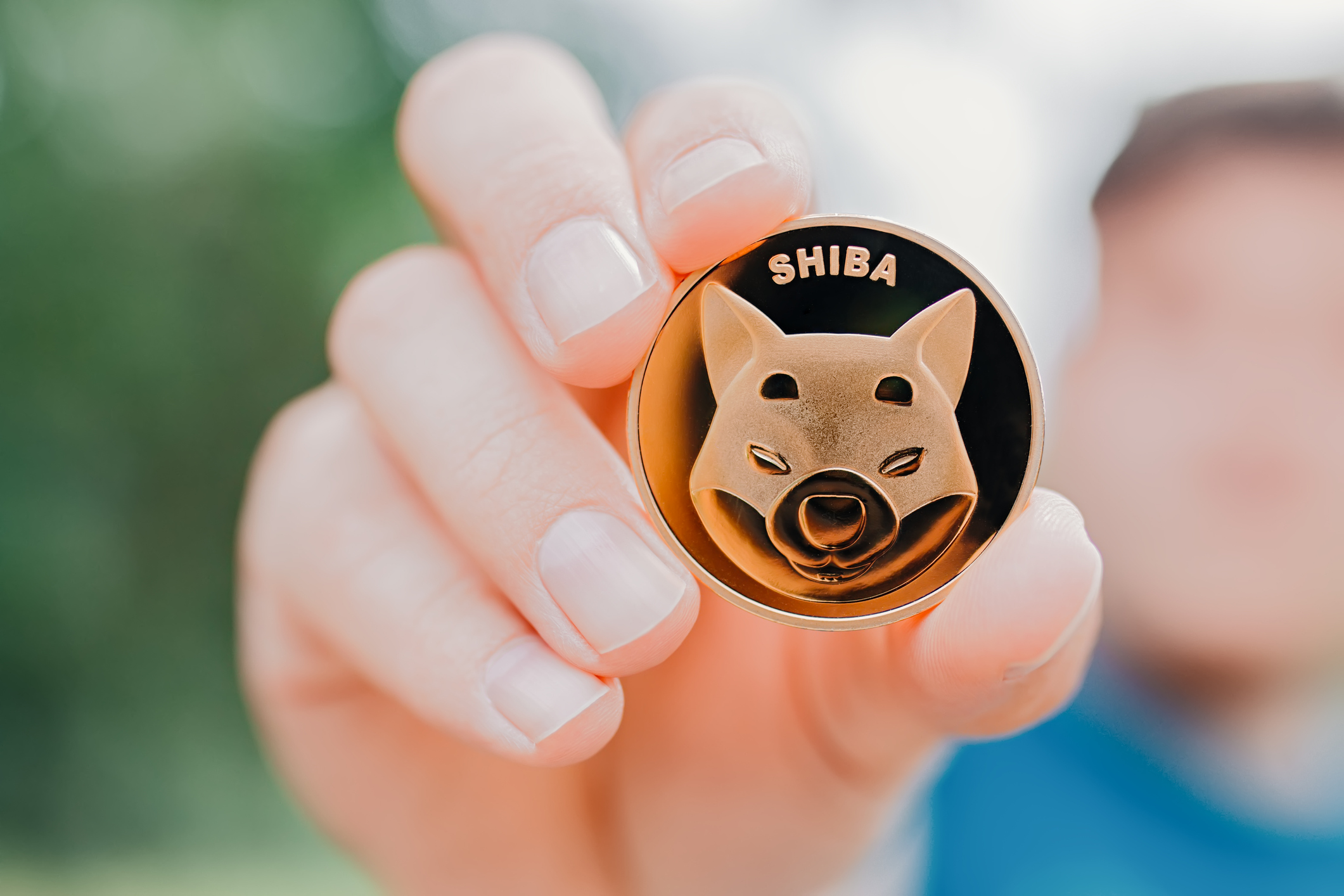 Man holding Shiba Inu token on natural background