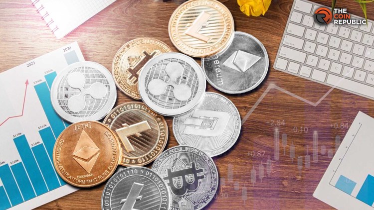 مجسمات معدنية لعملات رقمية على مكتب تعلوه مخططات بيانية ولوحة أزرار حاسوب