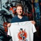 Martin Masser, ChangeNOW’s Director of Strategic Partnerships, holds a branded T-shirt in a graffiti-covered London passage.
